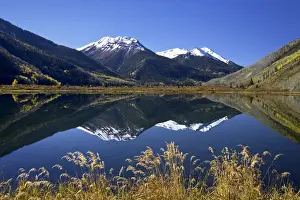 Snow-capped Red Mountain reflected in Crystal Lake with fall colors
