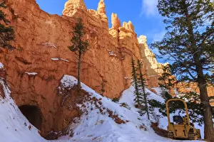 Tunnel Prints: Snow clearing equipment at a tunnel through sunlit red rock in winter