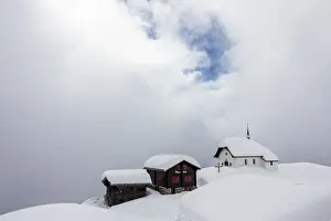 Ski Resort Prints: Snow covered mountain huts and church surrounded by low clouds
