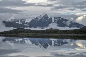 Altitude Prints: Snow-covered peak in Daxue Mountain Range reflects in Lenggacuo Lake at evening under soft light and clouds