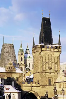 Mala Strana Prints: Snow-covered Romanesque and Gothic Malostranske Bridge towers and in the background the towers of the Baroque St