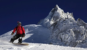 A snowboarder riding powder snow off the top of the famous Grand Montets ski area A snowboarder riding powder snow off the top of the famous Grand Montets ski area