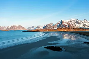 Nordland County Gallery: Snowcapped mountains reflected on Fredvang beach washed by waves at sunset, Nordland county