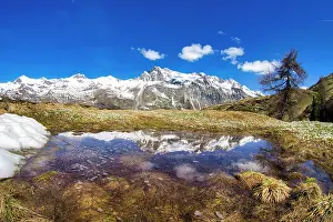 Engadine Prints: Snowcapped mountains reflected in a pristine lake in springtime