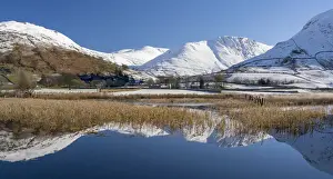 Snowclad sunlit fells around Hartstop reflected in Brothers Water, Lake District