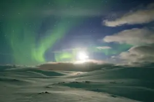 Nighttime Prints: Snowy landscape lit by moon in the starry sky during the Northern Lights (Aurora Borealis