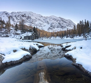 The snowy peaks reflected in the frozen Lake Mufule, Malenco Valley, Province of Sondrio