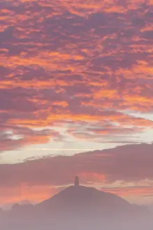 Back Lit Prints: Spectacular sunrise behind Glastonbury Tor on a misty autumn morning