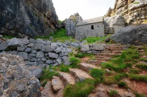 Chapel Prints: St Govans Chapel sits against a limestone cliff with steps leading to the entrance in Pembrokeshire