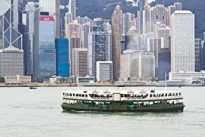 Star ferry crosses Victoria Harbour with Hong Kong Island skyline behind, Hong Kong, China, Asia