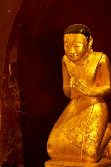 Statue at the base of the original Bagan-style standing golden Buddha statue which faces South Statue at the base of the original Bagan-style standing golden Buddha statue which faces South