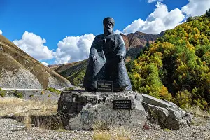 Identity Prints: Statue of a poet sitting on a large stone with mountains and trees in the background in a quiet area of South Ossetia