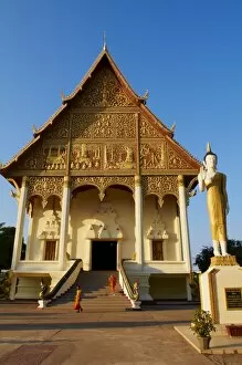 Images Dated 26th December 2010: Statue of standing Buddha and monks, Pha That Luang temple, Vientiane, Laos