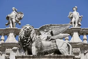Statue of winged Venetian lion in front of statues of Venus and Mercury on the top of the Palazzo Maffei, Verona