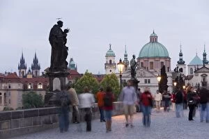 Statues and crowd on Charles Bridge, UNESCO World Heritage Site, with the dome of the church of St