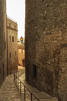 Girona Prints: Steep and narrow winding street in gorgeous medieval hilltop walled village, Pals
