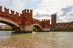 Riverside Prints: Stone bridge Ponte Scaligero spans River Adige near Castelvecchio castle in Verona Italy on a cloudy day
