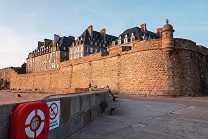 Fortifications Prints: Stone ramparts and town walls stand tall on seafront in Saint Malo as evening light casts shadows on the historical