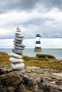 Nautical Prints: Stone tower stands in front of Trwyn Du Lighthouse in Anglesey, Wales under cloudy sky