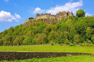 Stirling Prints: Stone wall and Stirling Castle on a hill in Stirlingshire region of Scotland surrounded by trees