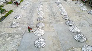Goods Prints: Storage structures hold rice in Dhaka while people move nearby on a clear day in Bangladesh