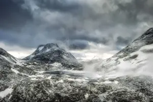 Storm clouds over Olaskarsvatnet lake at feet of the snowcapped Olaskarstind mountain