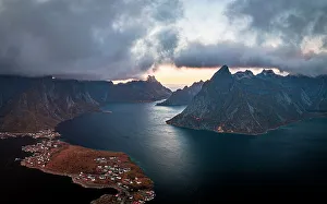 Reine Prints: Storm clouds at sunset over majestic mountains along a fjord