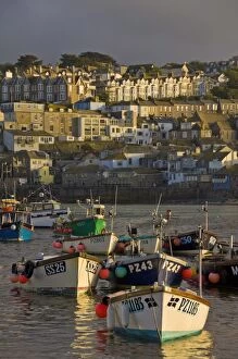 A stormy sky at sunset with small Cornish fishing boats in the harbour at St