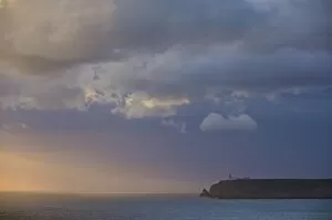 Stormy sunset over Atlantic ocean and cliffs at Cape St. Vincent with lighthouse in the distance