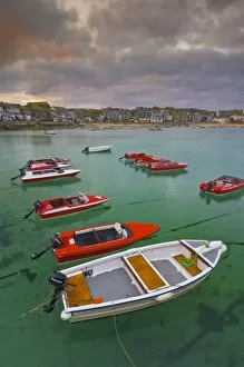 Strange cloud formation in a stormy sky at sunset, with small red speedboats for hire with an incoming tide in