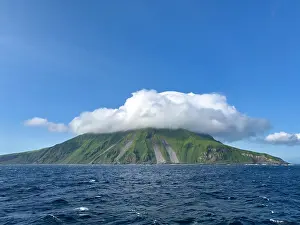Uninhabited Prints: Stratovolcano on Kagamil Island shows green slopes and clouds over the sea in Alaska's Aleutian Archipelago