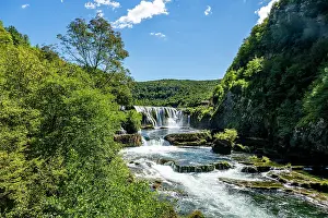 Flowing Prints: Strbacki buk waterfall in Una National Park flows over rocks and cascades through trees on a sunny day in Bosnia