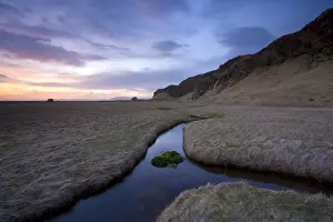 Stream meandering into the distance and reflecting colours in the twilight sky
