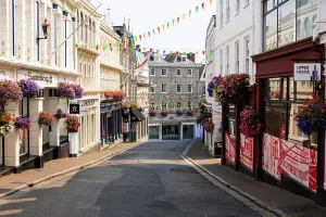 Quaint Prints: Street scene with flower baskets and bunting in St Peter Port showing vibrant local culture and community spirit