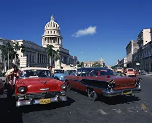 Taxi Prints: Street scene of old American automobiles used as taxis parked near the Capitolio Building in Central Havana