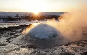 Geothermal Gallery: Strokkur Geysir erupting at sunrise during winter, geothermal area beside the Hvita River