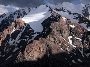 Breathtaking Views Prints: Stunning mountainous landscape of Kyrgyzstan illuminated by fading sunlight and shadowy clouds