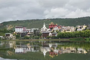 Getaway Prints: Stupas and Tibetan buildings reflect in Lamuyangcuo Lake with green hills in background in Shangri-La City Yunnan China