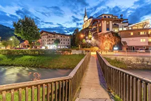 Alpine Prints: Summer dusk over river and church in Kaprun with buildings alongside in Salzburg region