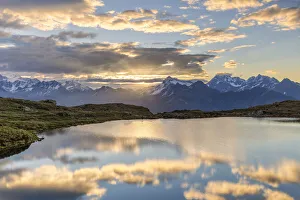 The sun and clouds is reflected in the Arcoglio Lake at sunrise, Valmalenco, Valtellina, Lombardy, Italy, Europe