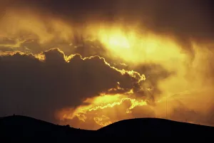 Skies Prints: Sun behind dark clouds at sunset over hills at Guanajuato