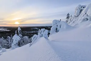 The sun frames the snowy landscape and woods in the cold arctic winter, Ruka, Kuusamo