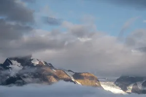 Alpenglow Prints: Sunlight breaks through clouds over Meili Mountains in Yunnan during early morning hours highlighting snow and rock
