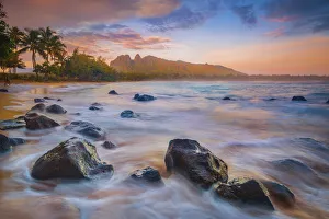 Sunrise over the calm bay waters at Anahola Beach Park, Kalalea mountain in the distance