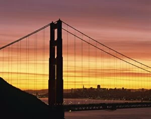 Sunrise at the Golden Gate Bridge, with city skyline in the background