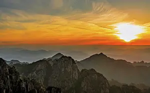 Trek Prints: Sunrise over the peaks of Huangshan in China with soft light illuminating the rocky landscape and distant mountains