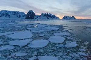 Sunrise on snow-covered mountains and dense sea ice in Neumayer Channel