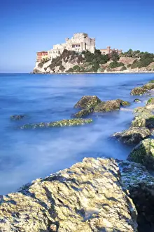 Sunrise on turquoise sea frames the medieval Falconara Castle, Butera, Province of Caltanissetta