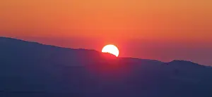West Prints: Sunrise view over Bryce Canyon with the sun rising over distant hills in Utah