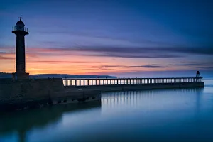 Sunset afterglow over Whitby West Pier and lighthouse, the North Yorkshire coast